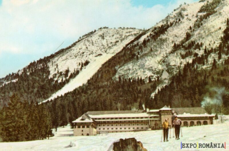 Peisaj montan cu schiori și hotel de iarnă