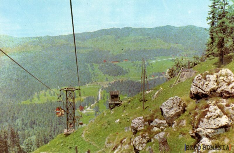 Peisaj montan cu teleferic și verdeață abundentă