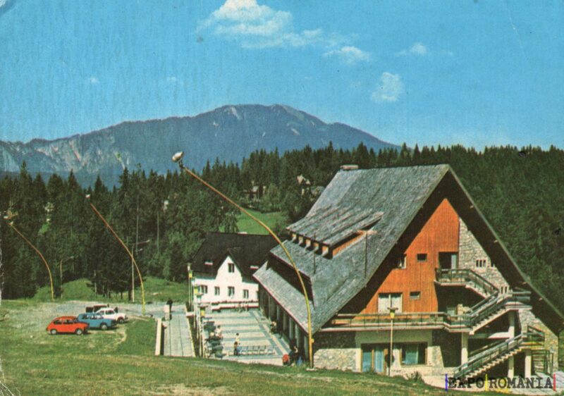 Peisaj montan cu cabane și mașini parcate